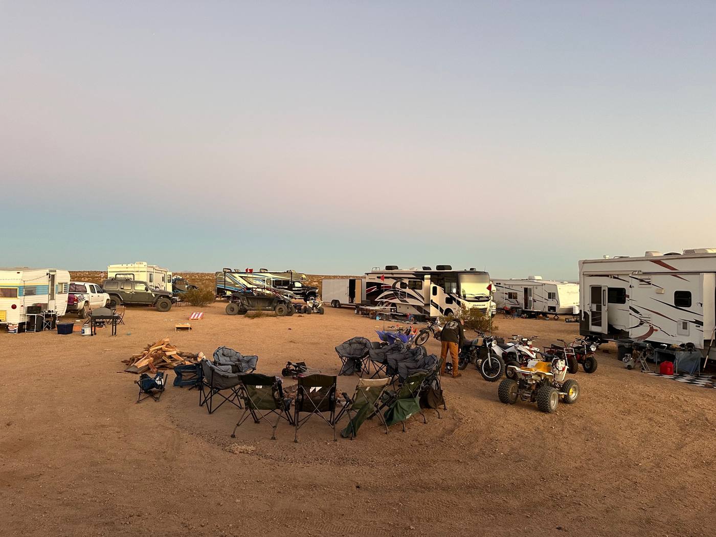 Desert campsite at dusk with RVs and off-road vehicles