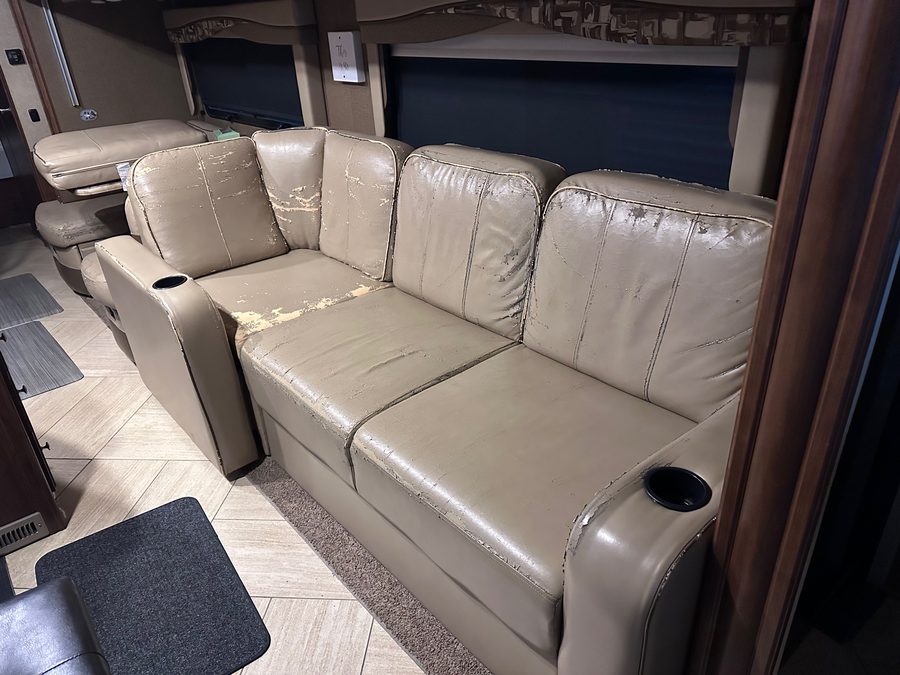 RV living area sofa before reupholstery, worn and cracked leatherette